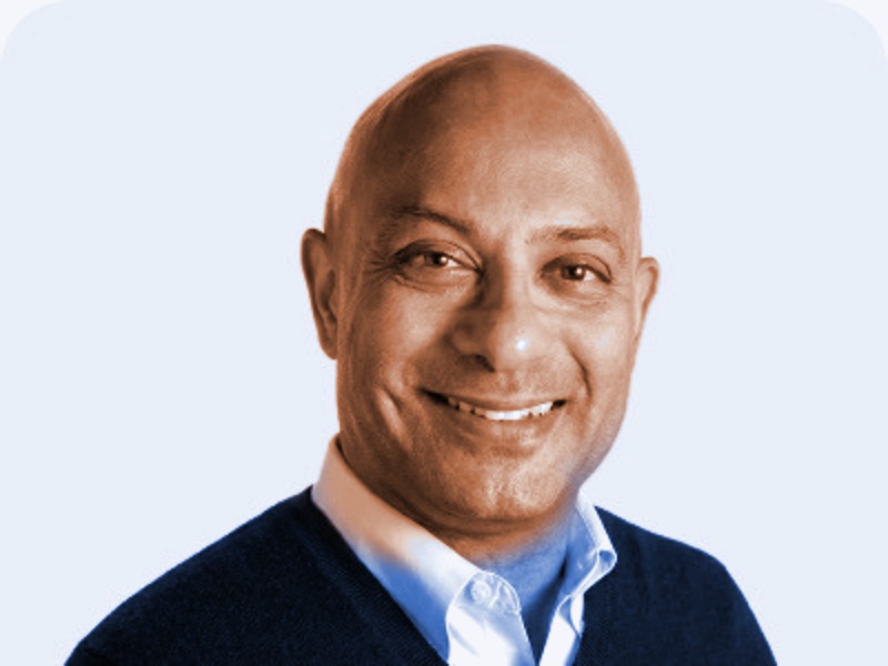 Portrait of Karim Ismail, smiling, in a dark sweater over a collared shirt